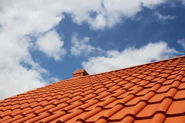 Toiture neuve en tuiles rouges sous ciel bleu